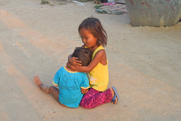 カンボジアスラムで弟の面倒を見る女の子